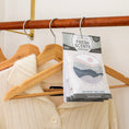 Load image into Gallery viewer, A cream sweater hangs in a closet, while the Fresh Scents Do What You Love - Sachet 3pk brings flameless fragrance and a minimalist landscape design as a long-lasting freshener.
