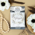 Load image into Gallery viewer, The Fresh Scents Blessed Wreath 3pk scented sachets feature a floral wreath design and the word "Blessed" on the box, shown with white flowers and wooden beads—an ideal flameless fragrance for any space.

