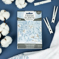 Load image into Gallery viewer, A Fresh Scents White Cotton - Sachet 3pk is displayed on a blue surface with cotton stems, a towel, and clothespins, capturing the fresh laundry vibe of this long-lasting flameless air freshener.
