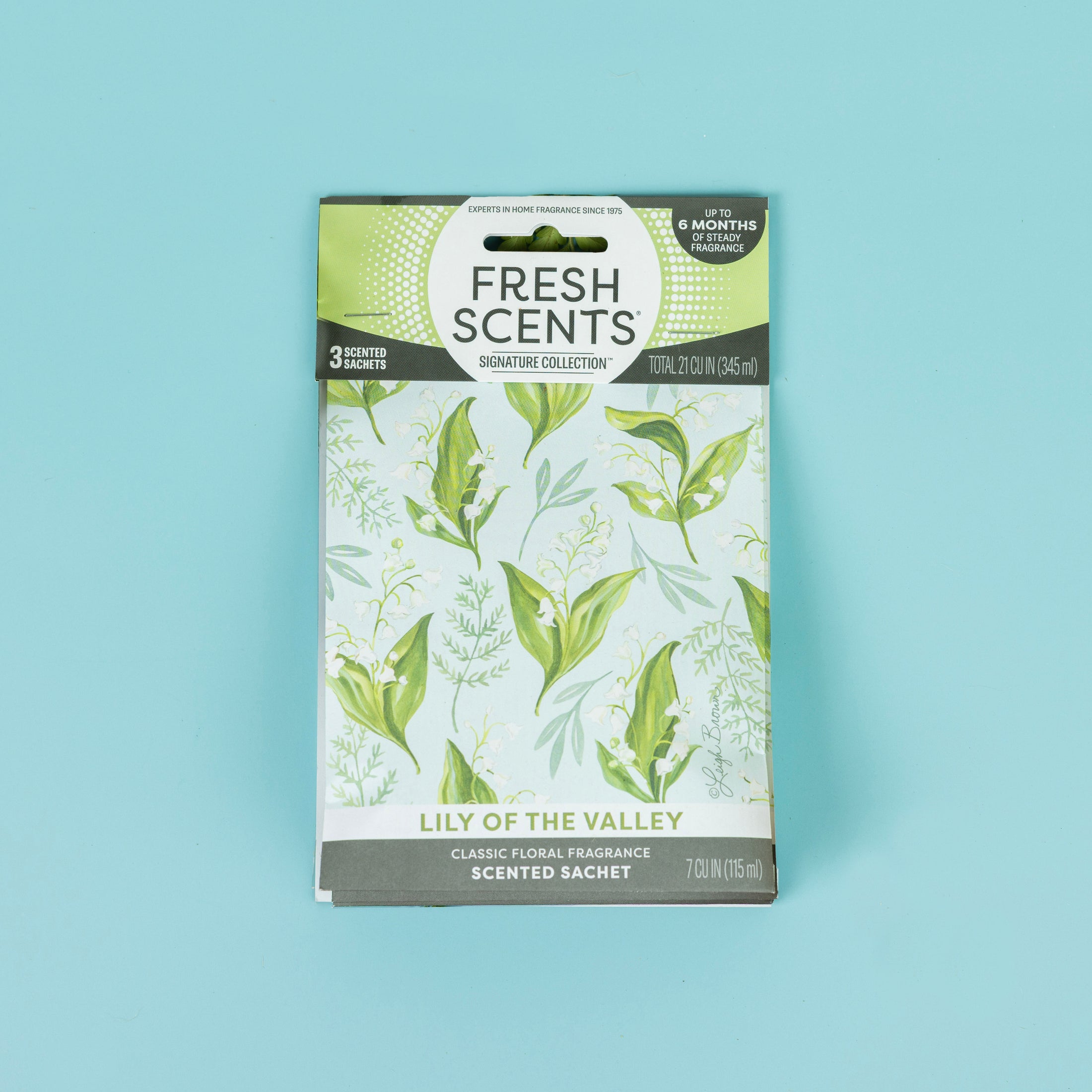 The Fresh Scents Lily of the Valley Sachet 3pk features green botanical designs on a light blue package. This flameless air freshener delivers a classic, long-lasting scent and contains 7 oz (115 ml).