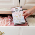 Load image into Gallery viewer, A hand places a Fresh Scents Little Sparkle - Sachet 3pk with the quote "She leaves a little sparkle wherever she goes" into a drawer of folded pink and cream sweaters, giving your wardrobe a long-lasting scent.
