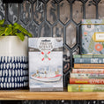 Load image into Gallery viewer, A decorative kitchen shelf displays a potted plant, Fresh Scents Watermark Sachet 3pk fresheners, a recipe tin, and colorful cookbooks set against a geometric tile backsplash.
