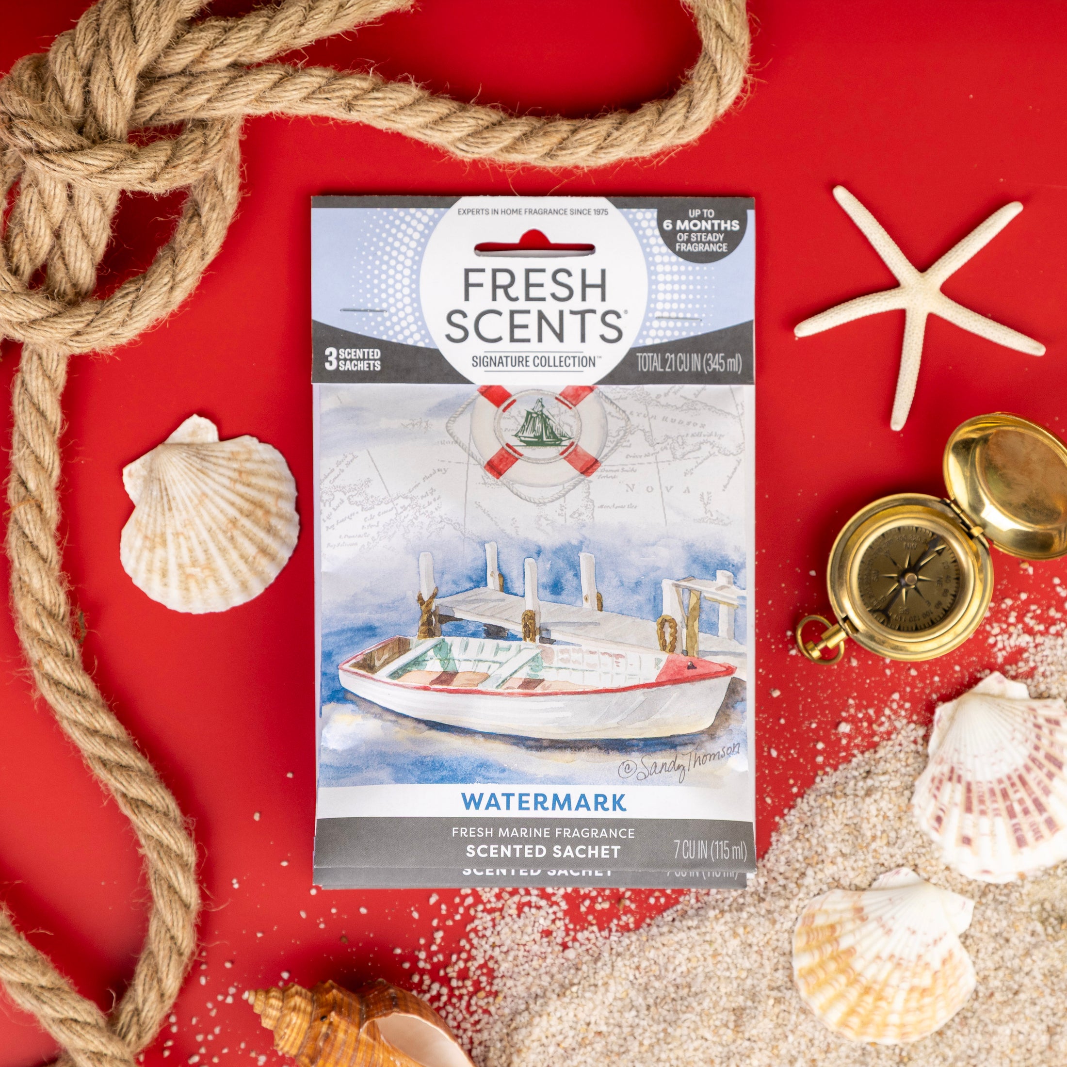The Fresh Scents Watermark - Sachet 3pk is displayed on a red background with nautical accents—a boat illustration, rope, seashells, sand, compass, and starfish—showcasing this flameless, long-lasting fragrance freshener.