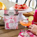 Load image into Gallery viewer, A pink cocktail with a lime slice sits on a wooden table next to a hand, pink napkin, Fresh Scents Disco Cowgirl Sachet 2pk box, chocolate-covered strawberries, a pink hat, and a sparkling disco ball.